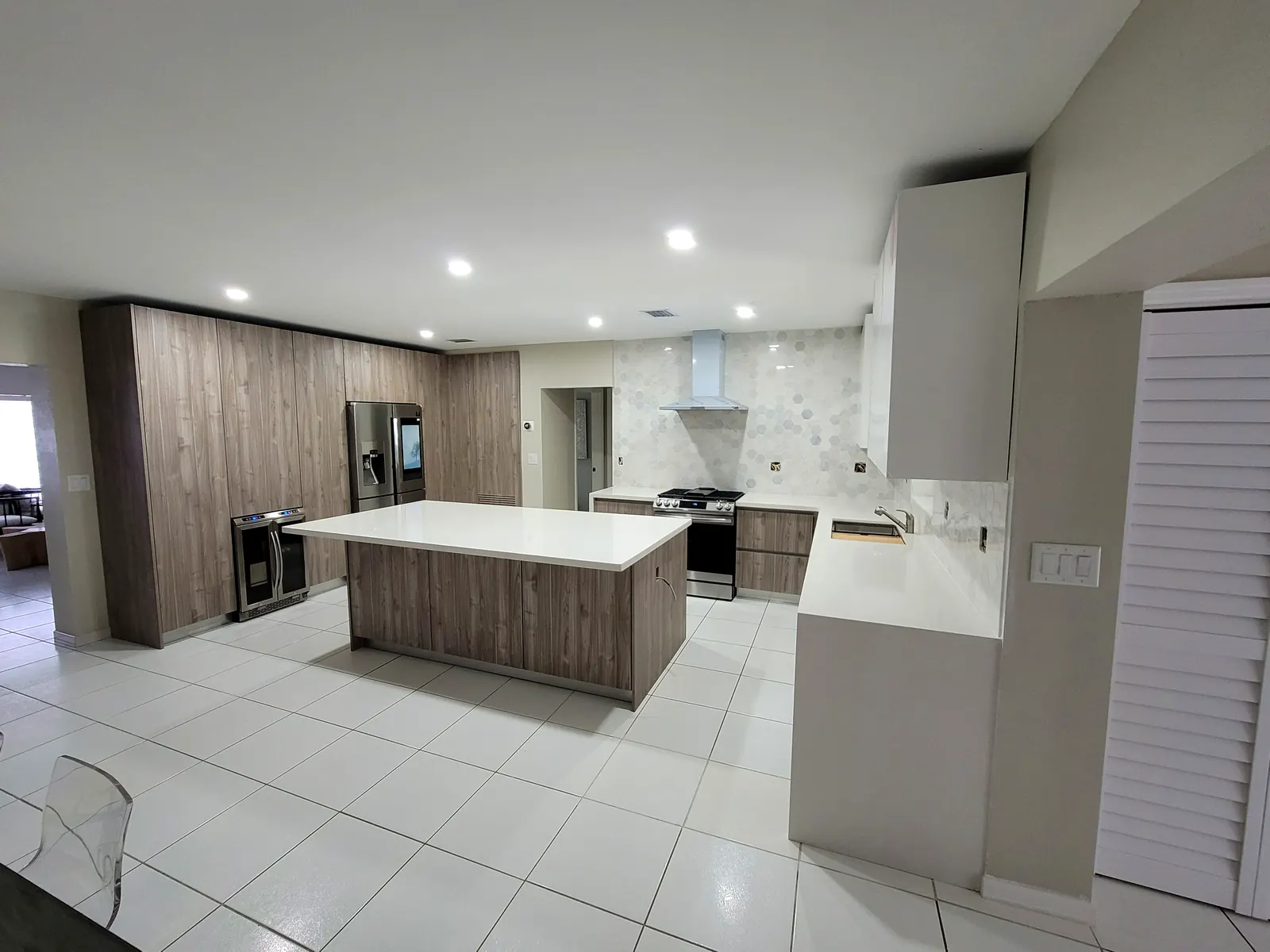 Custom walnut and white kitchen with large quartz island, built by Designs and Cabinets in Miami